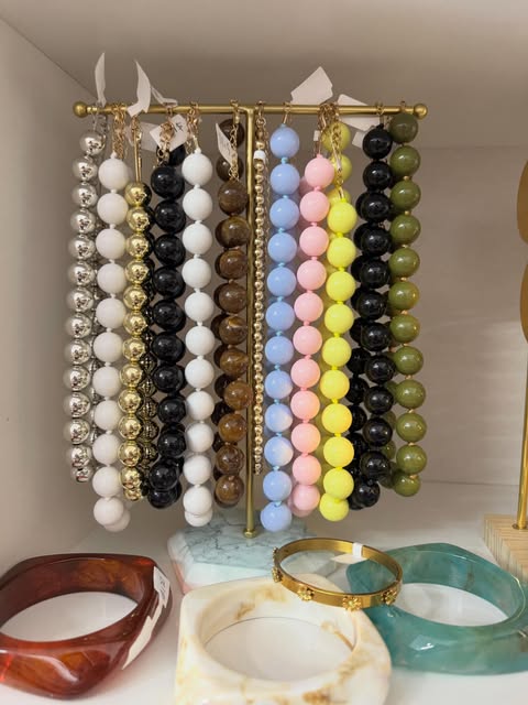 Collares de cuentas y pulseras en un exhibidor dorado.