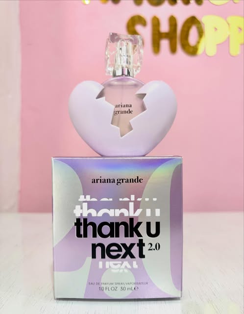Perfume Thank U Next de Ariana Grande, caja lila frente a la pared rosa.